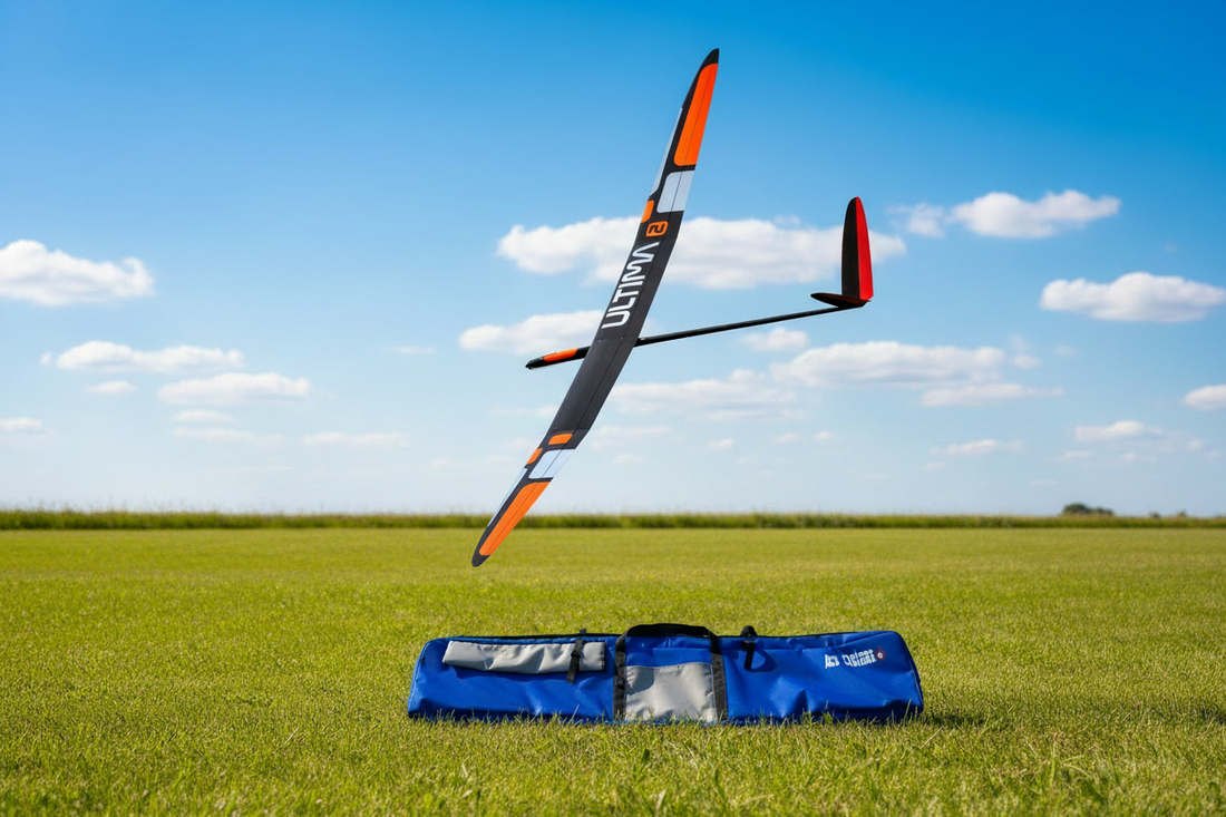RC glider in flight above a blue Ace Customs glider bag on a grass field